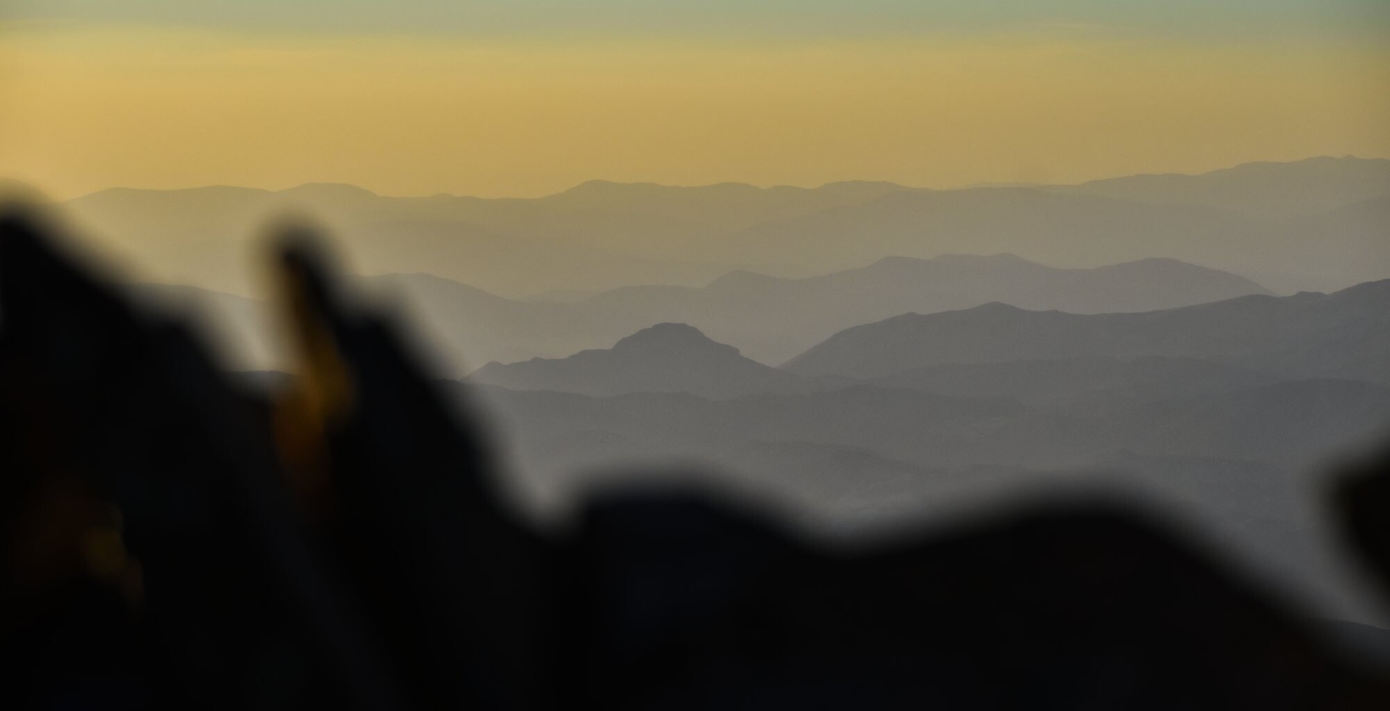 A photo of ridgelines of mountains appearing in the setting sun