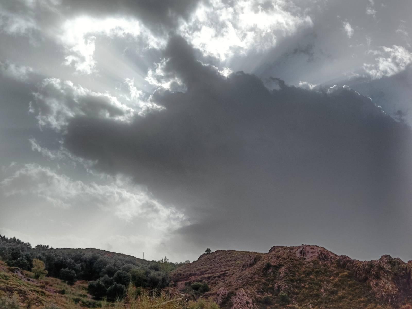 A cloud in the shape of a pig, looks like it's jumping over the hill underneath it!