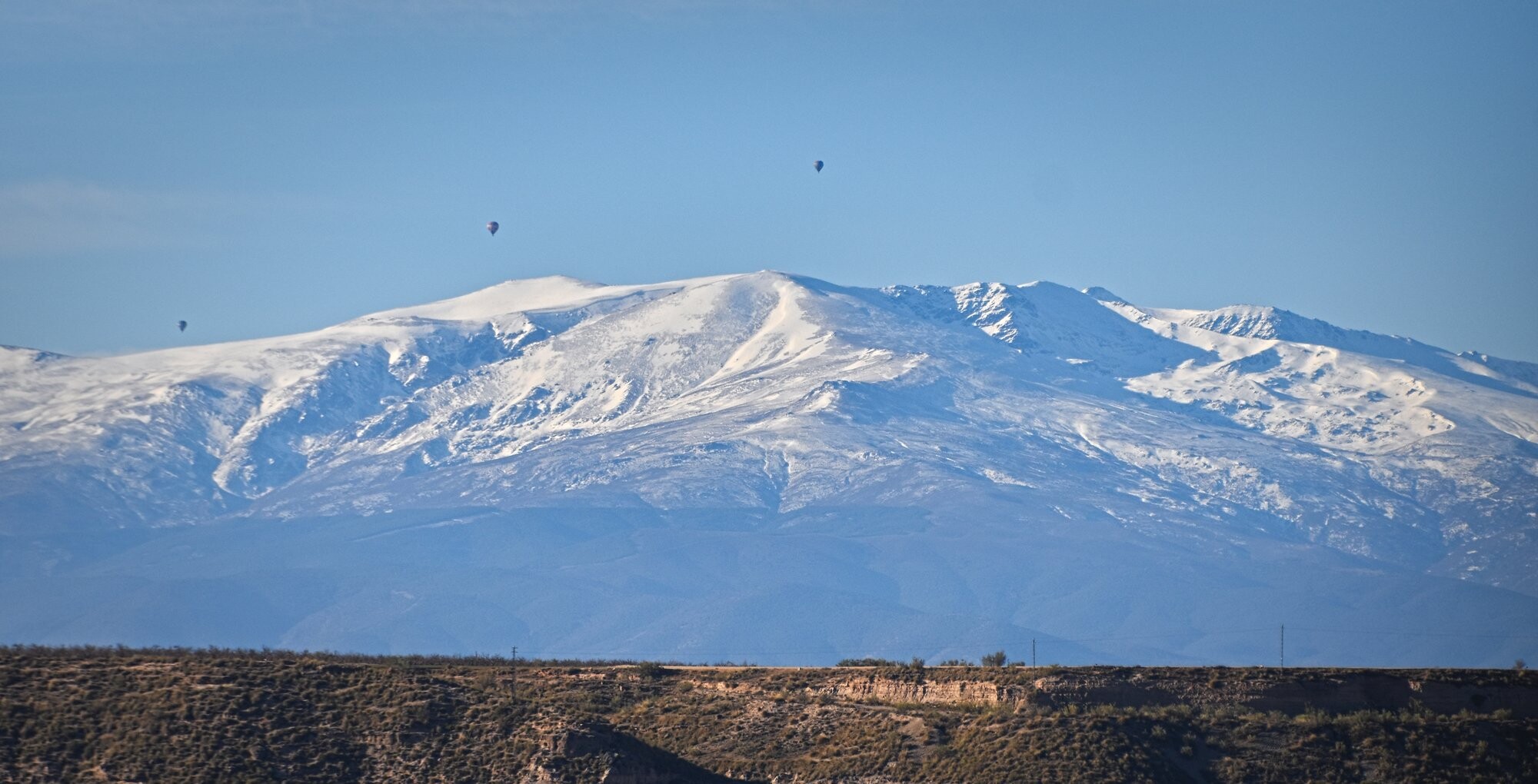 Three hotair balloons flying over the snowy mountains of the Sierra Nevada in Spain