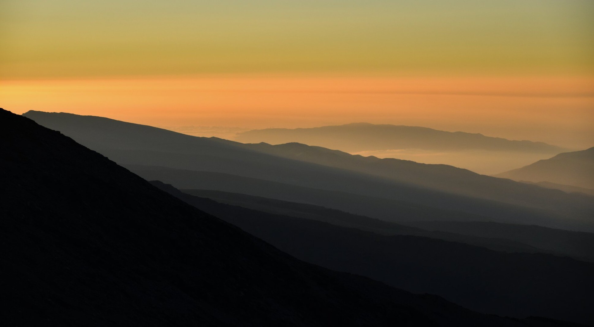 Another view of ridgelines of mountains in the setting sun with the orange glow over the Mediterranean sea