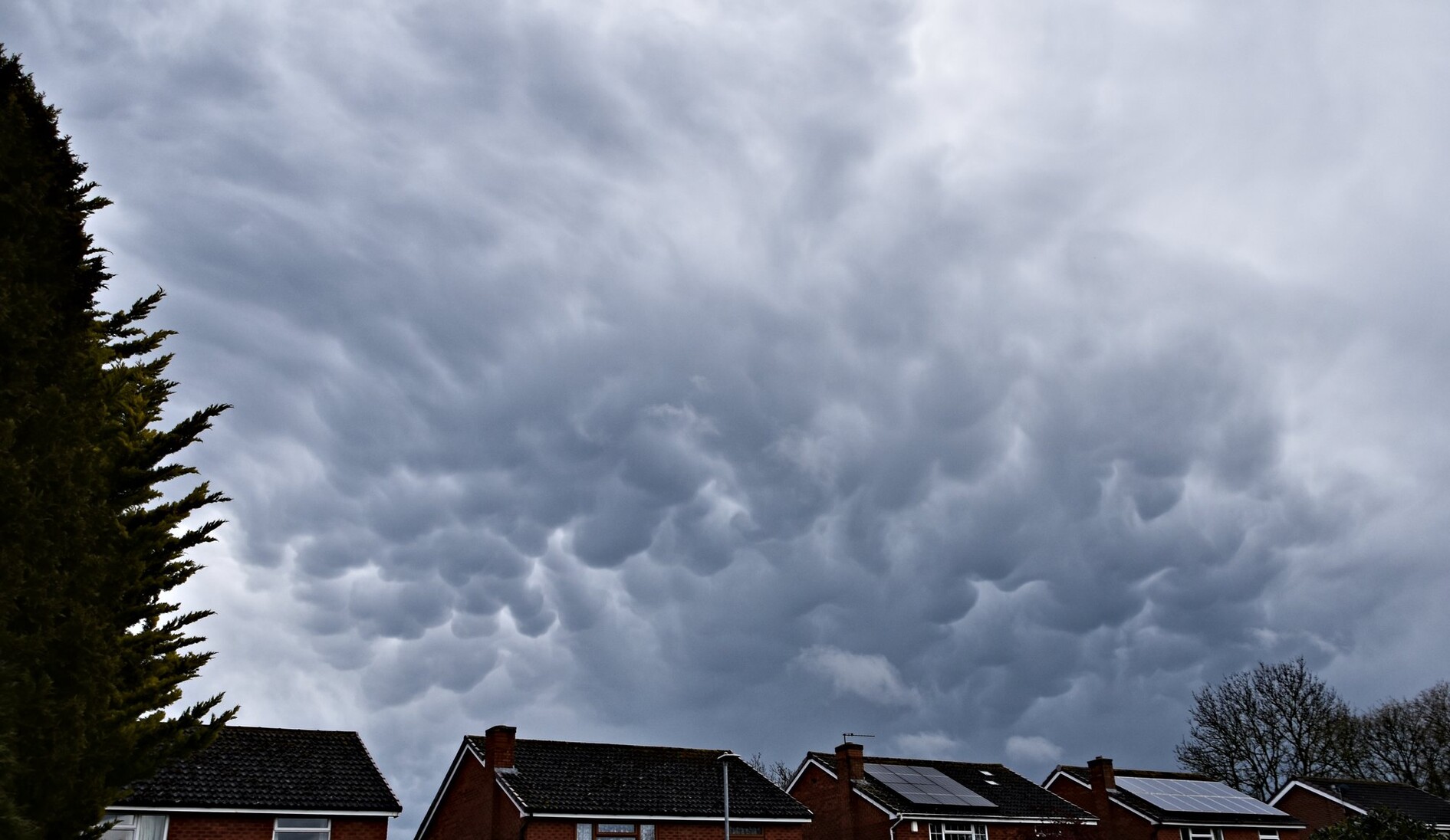 A view over house rooftops with Mammatus clouds in the sky